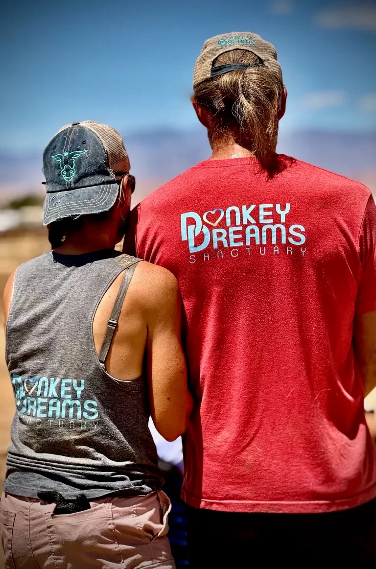 Two in Donkey Dreams Sanctuary shirts, looking out over the desert together